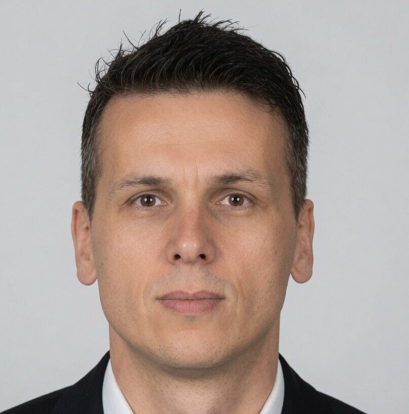 Professional headshot of Sasa Nikolic, a strata property management consultant in Surrey BC, wearing a black suit jacket and black tie against a light background