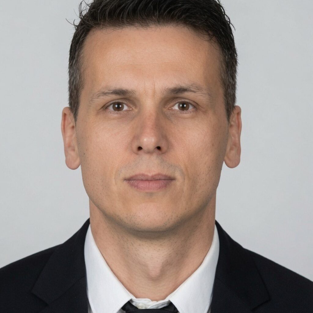 Professional headshot of a man in a black suit and white dress shirt against a neutral background, representing strata property management expertise in Surrey BC